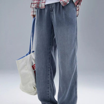 Men's wide leg relaxed fit jeans in washed lyocell fabric with drawstring and slight stretch, styled with casual sneakers and tote bag.